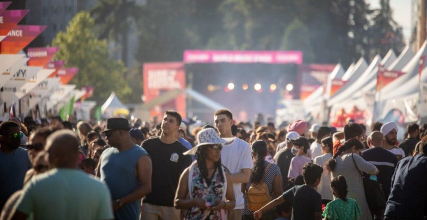 Large crowd enjoying a cultural festival in Surrey with tents, music, and performances.