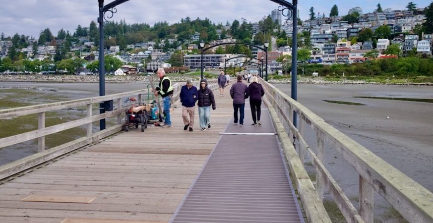 Visitors walk along the White Rock Pier where new accessibility priority signs will be installed following council approval.